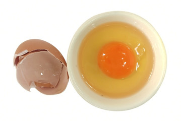 Raw egg in cup and broken egg shell on white background