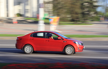Plakat Red car on the street with the effect of blurring the day