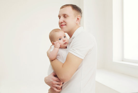 Happy father hugging his baby at home in white room