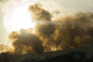 Obraz na płótnie Canvas Fire with smoke and a giant sun on the background