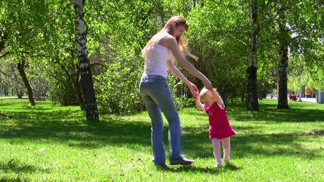 The young woman walks with the little girl in park
