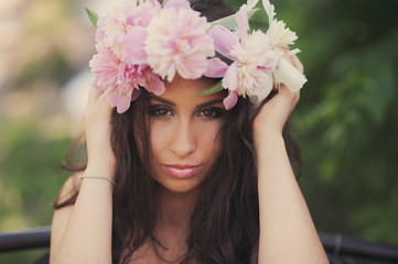 Obraz premium Portrait of a beautiful brunette girl in a wreath of peonies