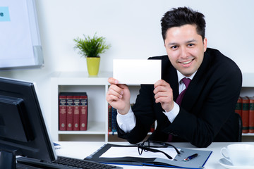 attractive business man in office holding a blank card