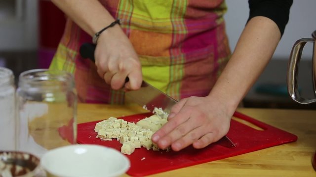 Close-up on female hands cutting a block of white chocolate