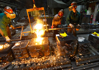 Industriearbeiter in einer Giesserei gießen Metall in die Form