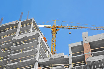 Crane and building construction site against blue sky