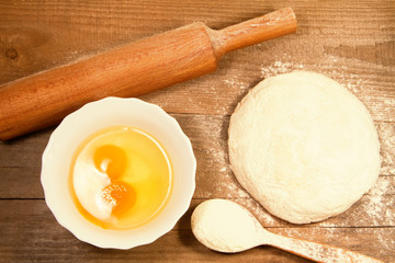 Fototapeta na wymiar homemade baking. Fresh dough for pastry, kitchen rolling pin, spoon flour, broken eggs on a chopping Board