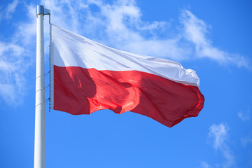 Naklejka na ściany i meble Polish flag on a background of blue sky
