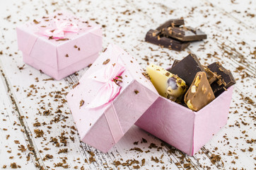 Gift box full of chocolate on white wooden table