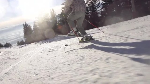 Slow Motion Rear View Of Skier Carving Down The Slope With Beautiful Sun Flares