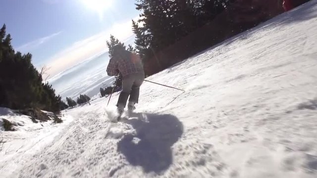 Slow Motion Rear View Of Skier Carving Down The Steep Slope With Sun Flares