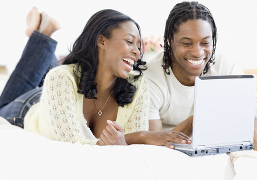 African couple on laptop in bed