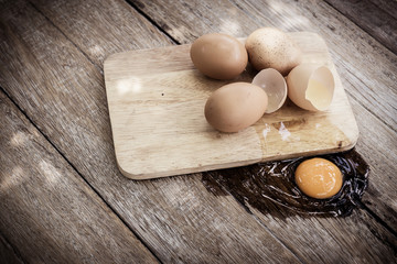 Broken egg on a wooden cutting board on wooden background.