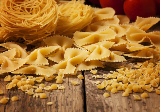 Variety of pasta on a wooden table, selective focus - Powered by Adobe