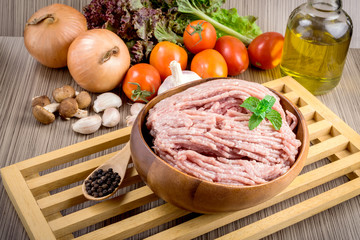 Raw ground meat in wood bowl.