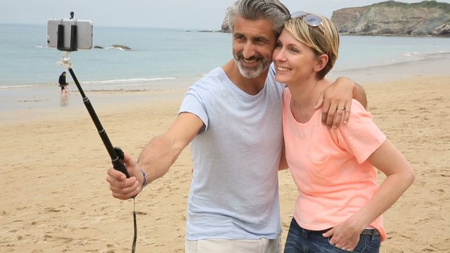 Couple taking picture with smartphone and extendable monopod