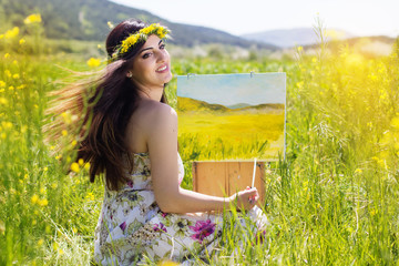 Naklejka na ściany i meble Pretty painter woman is create picture in a field