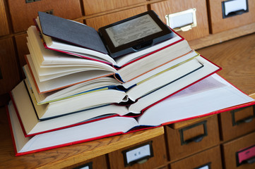 E-book Reader on top of Stack of Books in a Library