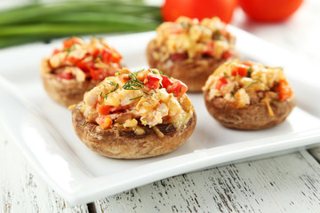 Stuffed mushrooms on plate on white wooden background