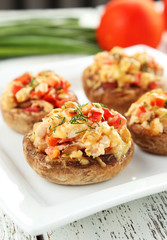 Stuffed mushrooms on plate on white wooden background