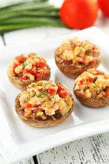 Stuffed mushrooms on plate on white wooden background