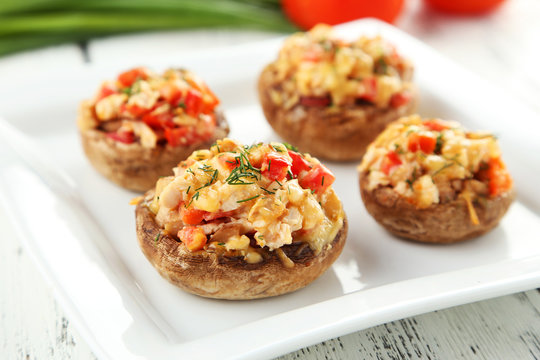 Stuffed mushrooms on plate on white wooden background