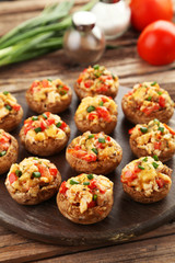 Stuffed mushrooms on cutting board on brown wooden background