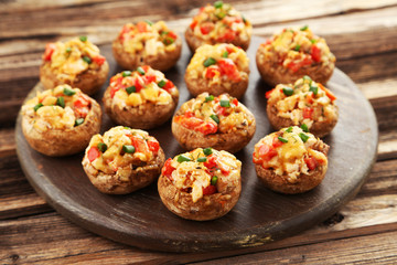 Stuffed mushrooms on cutting board on brown wooden background