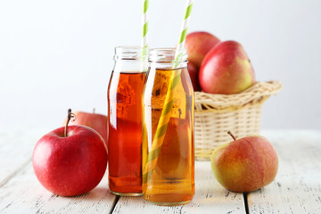 Bottles of apple juice with apples on white wooden background