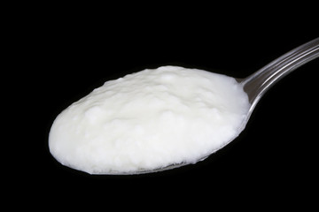 Spoon of yogurt isolated on black