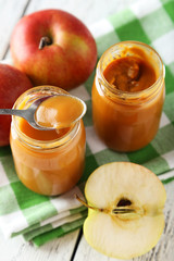Jars of baby puree with apples on white wooden background