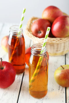 Bottles of apple juice with apples on white wooden background