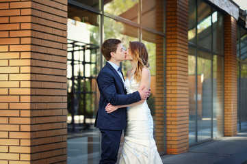 Fototapeta premium bride and groom stand on the corner of a brick building