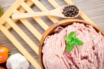 Raw ground meat in wood bowl.