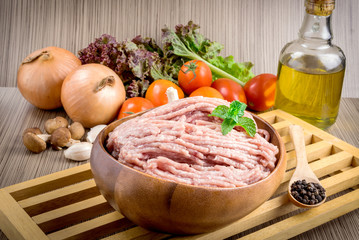 Raw ground meat in wood bowl.