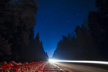Gordijnen Night sky with stars, road with traces of ligt and the forest © idea_studio