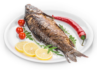 Grilled carp with vegetables on plate.