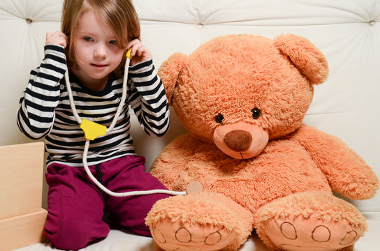 Cute, Blonde Girl Playing Doctor With Plush Toy Bear 