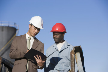 Multi-ethnic businessman and construction worker looking at paperwork