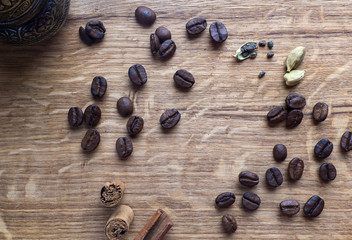 Coffe beans, cardamom and cinamon on wooden desk