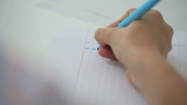 Closeup of hand writing alphabet on notebook page