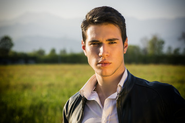 Handsome young man at countryside, in front of field or