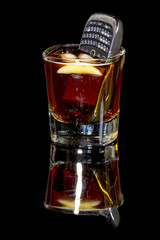 Whiskey and ice in a glass with a phone