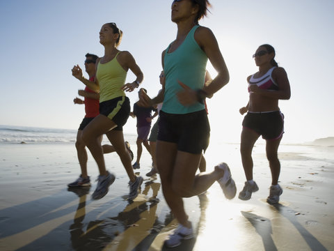 Multi-ethnic runners racing at beach - Powered by Adobe