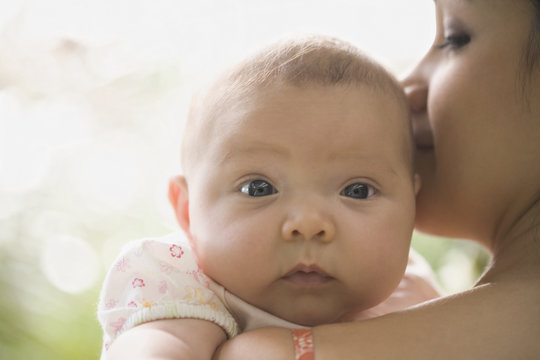 Hispanic baby looking over mother's shoulder