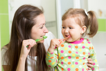 mother teaching child teeth brushing