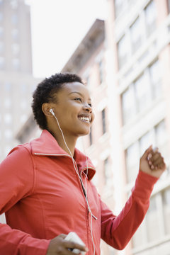 African woman listening to mp3 player while walking outdoors