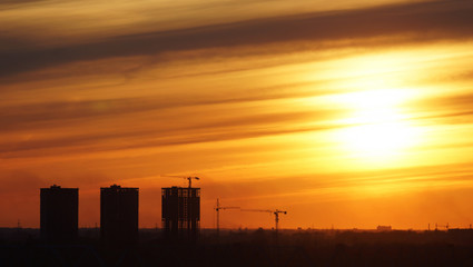 Outlines of houses under construction against the sunset