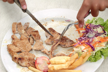 steaks and vegetable salad with french fries.
