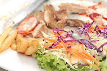 steaks and vegetable salad with french fries.